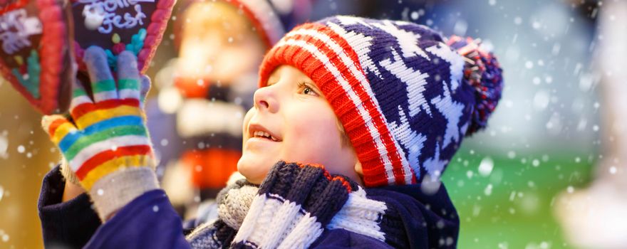 Kleiner Bub schaut Lebkuchenherz auf Weihnachtsmarkt an