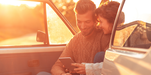 Pärchen sitzt im Auto und berechnet Kosten einer Autoversicherung