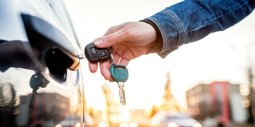 Person sperrt das Auto mit einem Autoschlüssel auf
